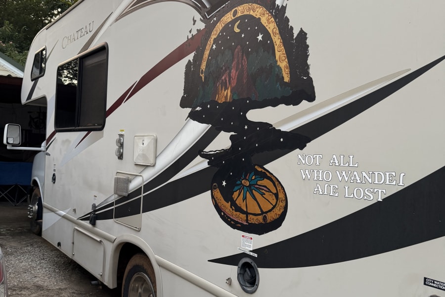 A white Chateau **rv rental** customized with a unique mural of a starry night, trees, and a compass for adventurous journeys.