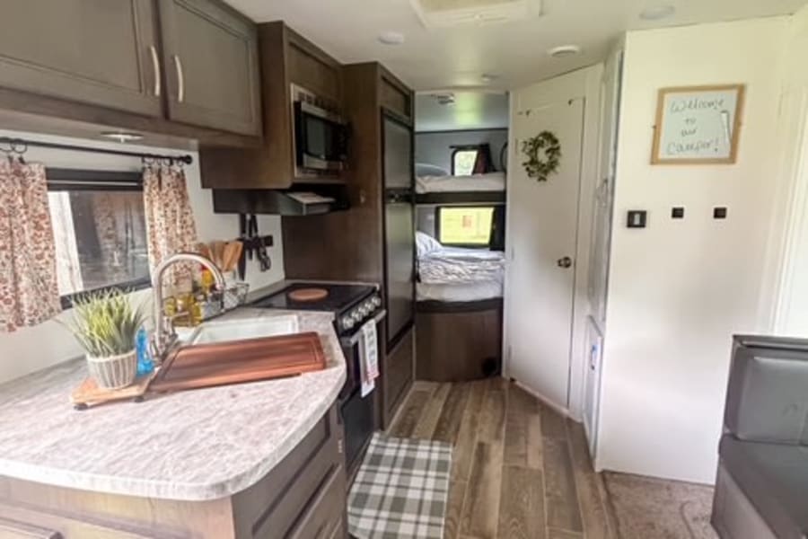 Spacious RV rental interior with a fully equipped kitchen, bunk beds, and a cozy dining area, perfect for adventurers.