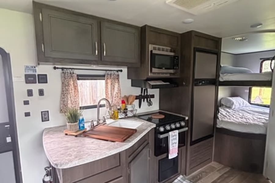 Spacious RV rental interior featuring a full kitchen, bunk beds, and modern amenities, ideal for travel and camping.