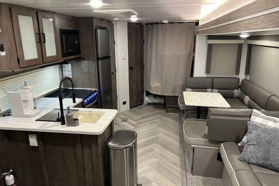 Spacious RV rental interior featuring a modern kitchen with a sink & microwave, and a comfortable dining/living area.