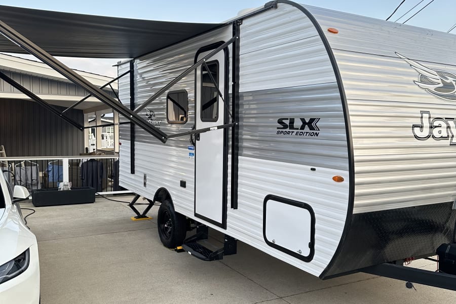 Jayco SLX Sport Edition travel trailer with extended awning on concrete pad, ready for rv rental. Blue sky and moon visible.