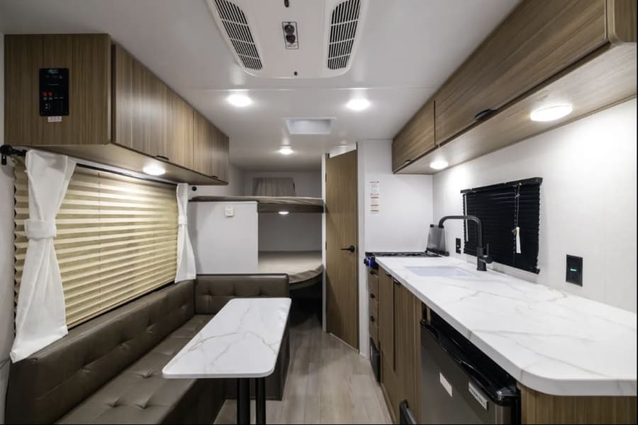 Tour this RV rental's cozy interior, complete with a functional kitchen, dinette, and rear bunk beds.