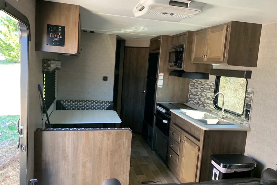 Experience comfort in this rv rental. View of kitchen, dinette, and living area in a modern travel trailer interior.