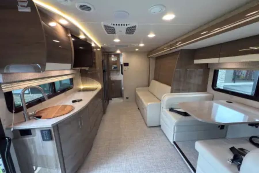 Spacious and clean rv rental interior with a fully equipped kitchen, comfortable lounge, and bright lighting.