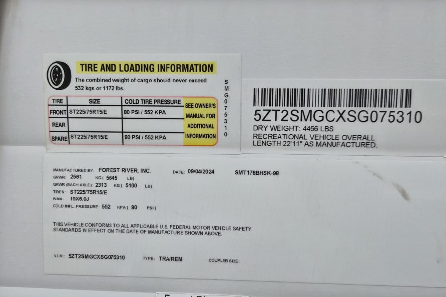 An RV rental's vehicle info label shows tire pressure (80 PSI), weight capacity, VIN, and other specs for safe operation.