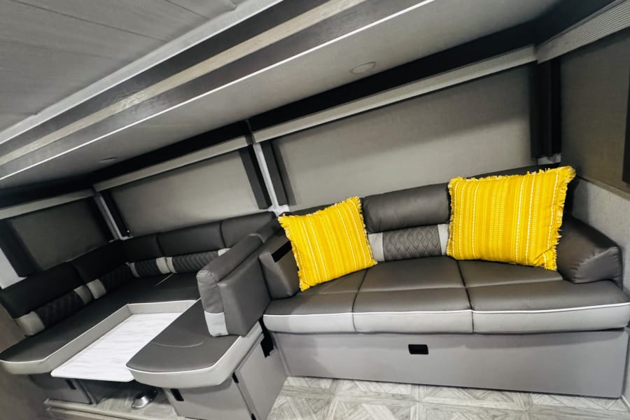 Modern gray L-shaped seating with bright yellow pillows inside a clean RV rental interior.