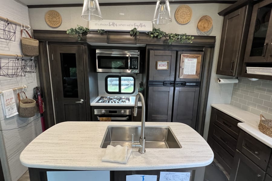 Modern and cozy RV rental kitchen with island sink, stove, and microwave. Perfect for a comfortable travel adventure.