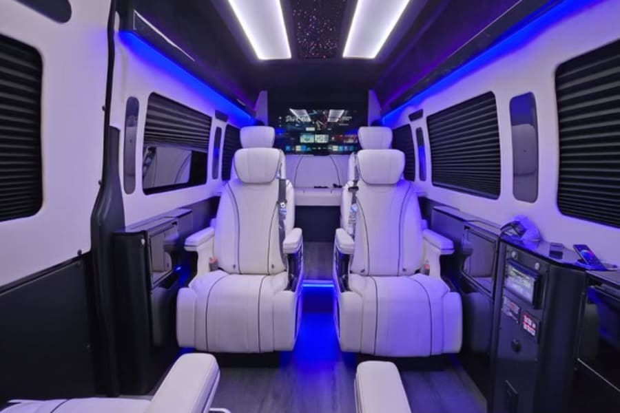 Luxurious RV rental interior: white leather captain's chairs, blue accent lighting, and a starlight ceiling for premium travel.
