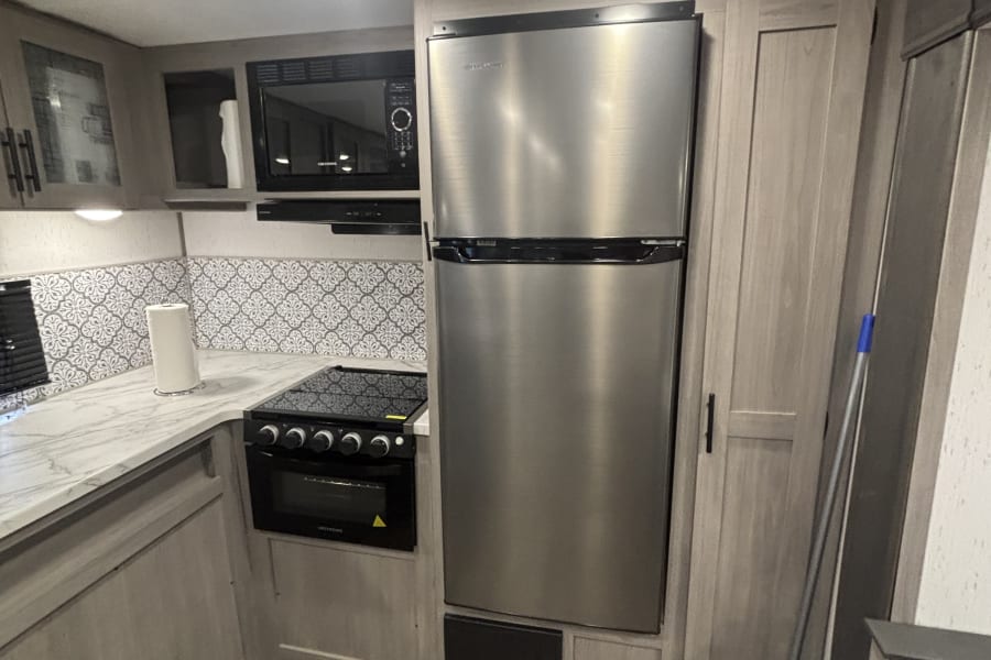 Explore the compact yet fully-equipped rv rental kitchen with stainless steel appliances, patterned backsplash, and modern cabinets.