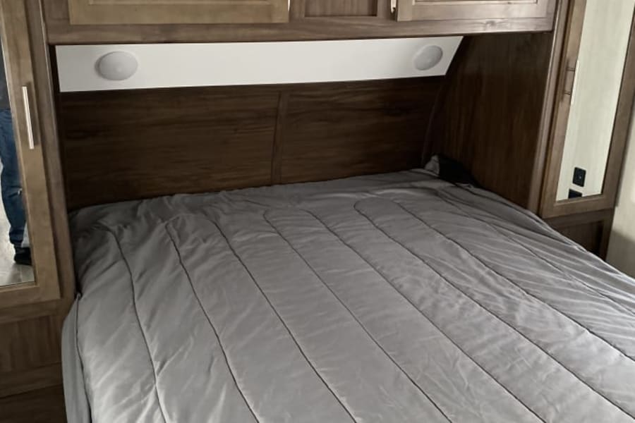 Cozy RV rental bedroom featuring a comfortable bed, overhead storage, and built-in reading lights for a relaxing trip.