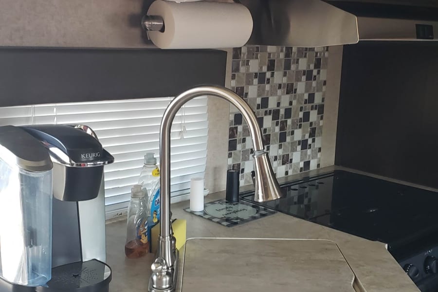 Functional RV rental kitchen with Keurig, sink, microwave, and stylish backsplash for comfortable travel cooking.