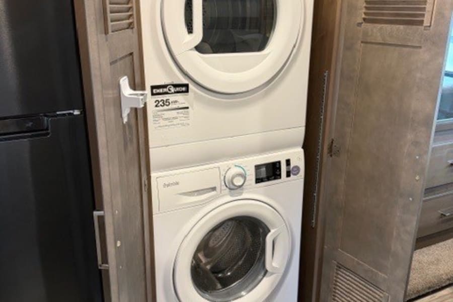 This RV rental features a stacked Splendide washer and dryer unit in a wooden cabinet, offering convenient onboard laundry facilities.