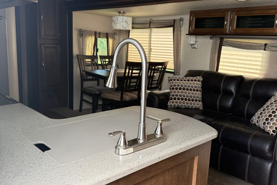 Enjoy this RV rental's spacious interior: a modern kitchen with sink, cozy dining area, and plush couch.