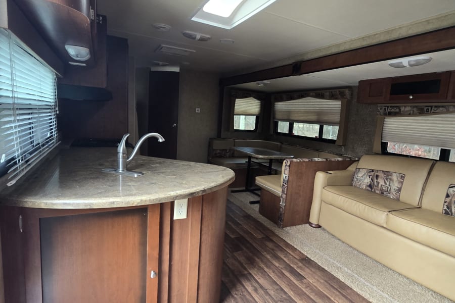 Step inside this RV rental, featuring a functional kitchen, cozy dinette, and comfortable living space with a sofa.