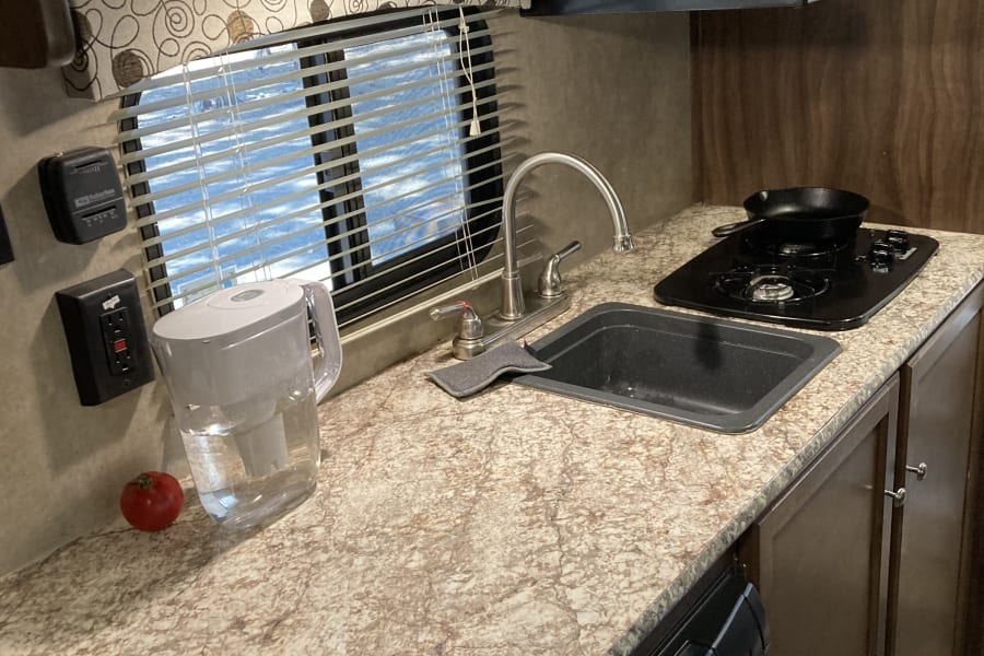 A well-equipped RV rental kitchen with a sink, stove, microwave, and Dometic fridge for your next adventure.