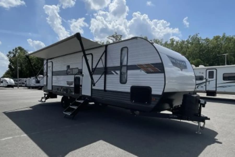 This white travel trailer with its awning extended is ready for your next RV rental adventure.
