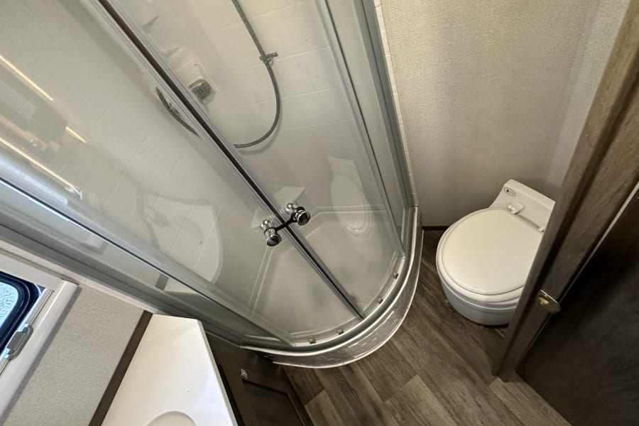 Compact RV rental bathroom with shower, toilet, and vanity area, perfect for comfortable travels.