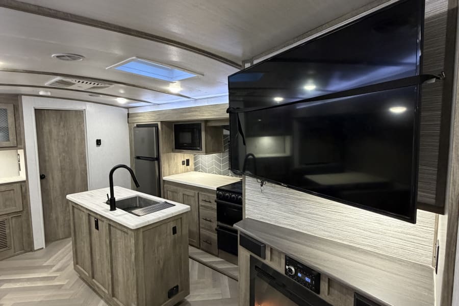 Experience comfort in this RV rental! Features a contemporary kitchen, island, and living space with TV and electric fireplace.