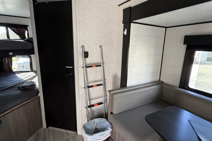 This RV rental features a cozy dinette with seating & table, bunk beds, and durable wood-look flooring for travel comfort.
