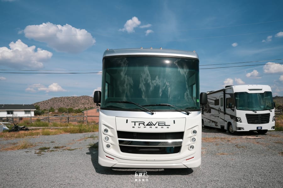 Two modern white RVs, a Travel Supreme and an FR3, parked on a gravel lot. Plan your next rv rental journey!