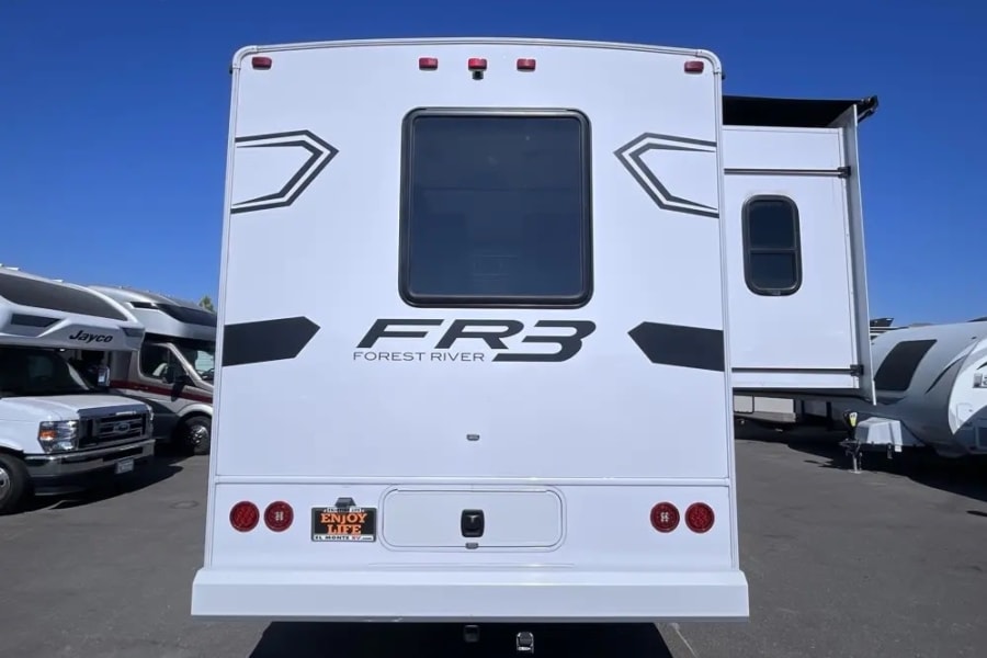 White Forest River FR3 RV rental, rear view. El Monte RV plate holder visible on a sunny lot.