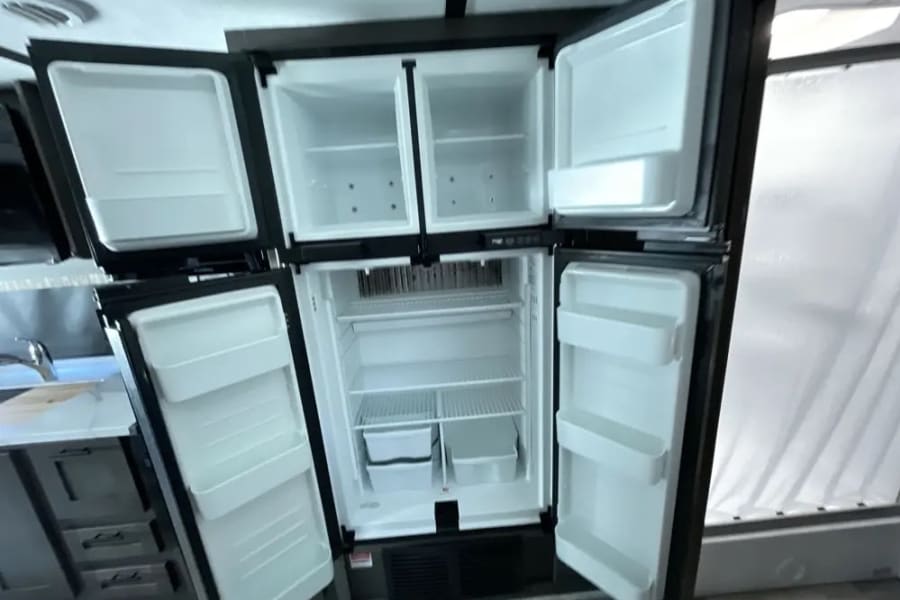 RV rental's spacious, empty four-door refrigerator and freezer, ready for your travel needs.
