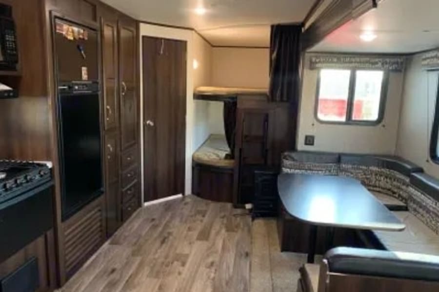 Spacious RV rental interior featuring a kitchen, bunk beds, and a comfy dinette. Ideal for travel adventures.