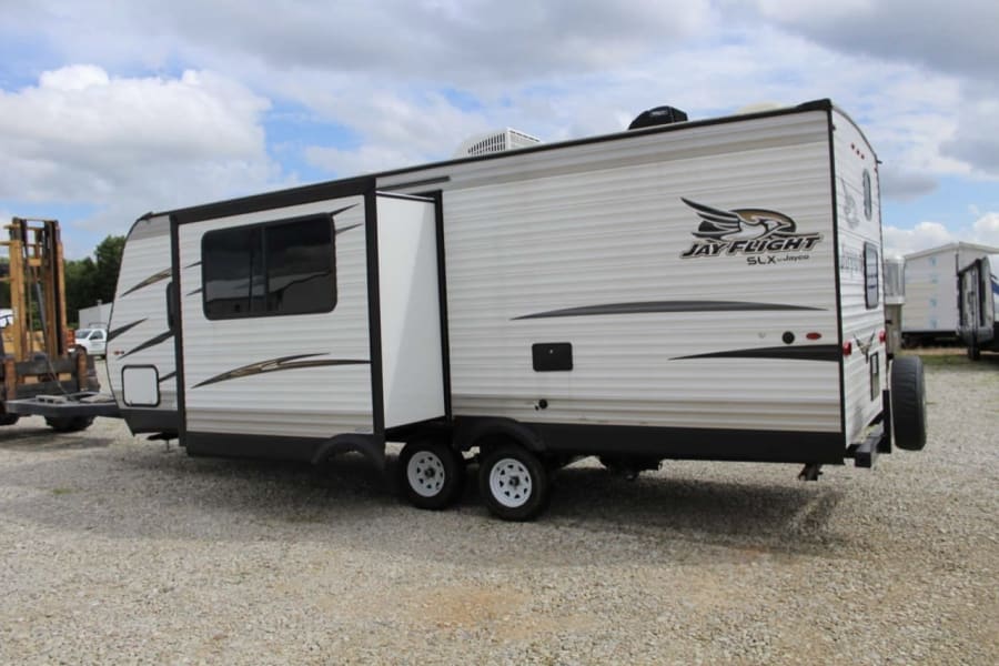 Jayco Jay Flight SLX travel trailer RV rental with extended slide-out, parked on gravel, ready for adventure.