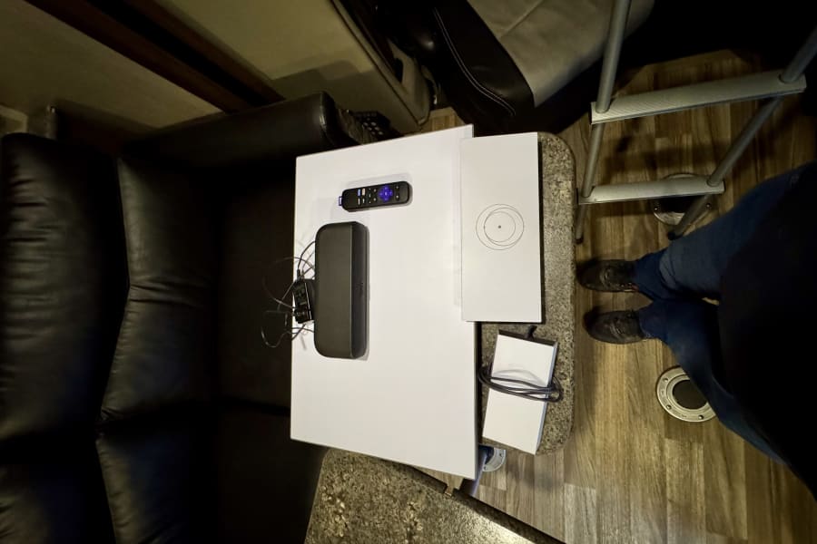 RV rental interior: Compact entertainment tech setup featuring a Roku remote, device, and ladder for convenience.