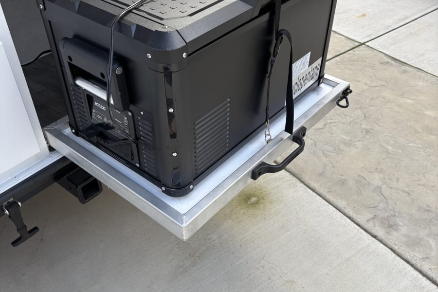 Ready for your RV rental adventure: An ICECO portable fridge securely on a pull-out tray, perfect for outdoor camping.