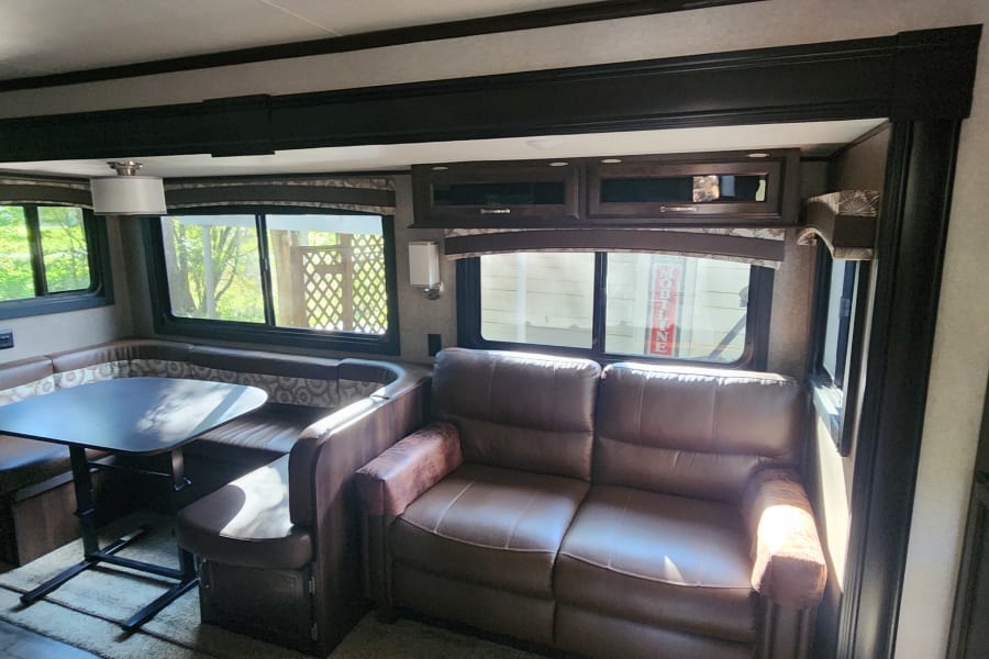 Comfortable RV rental interior: a cozy dinette, plush sofa, and large windows bringing in natural light. Perfect for travel!