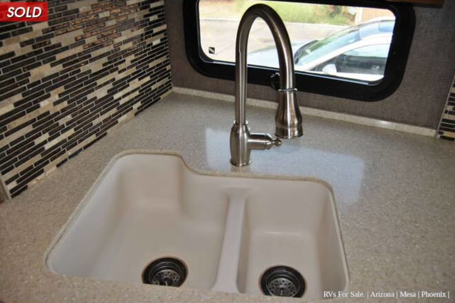 Modern RV rental kitchen with a large double sink, pull-down faucet, and stylish mosaic backsplash over spacious counters.