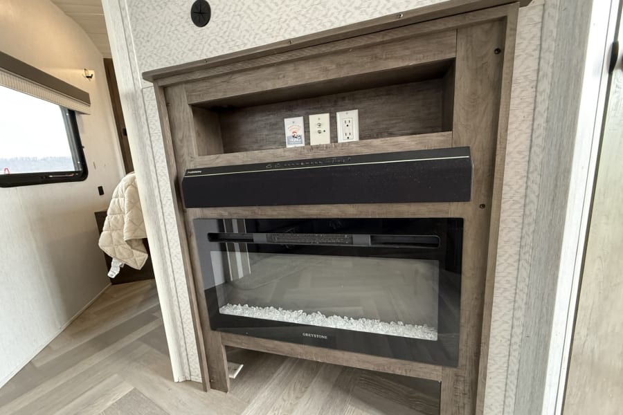RV rental: modern entertainment unit with a Furrion soundbar, Greystone electric fireplace, and power/cable outlets.