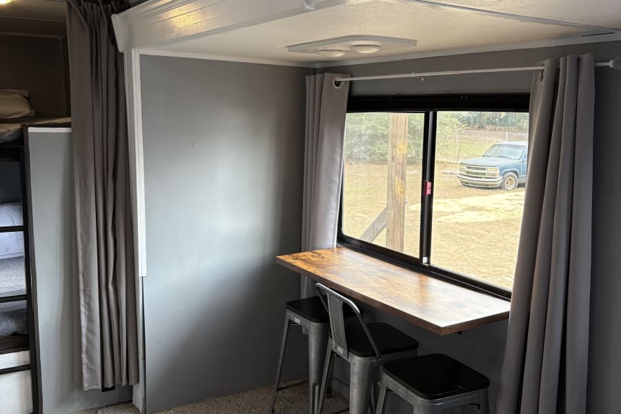 Cozy RV rental interior showing dining bar, window view, and bunk beds.
