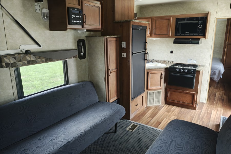 Spacious rv rental interior featuring a full kitchen, two sofas, and a rear bedroom visible.