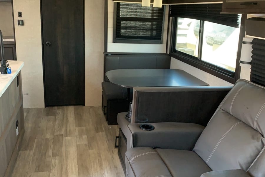 Inside this RV rental, find a cozy dinette, comfortable recliners with cup holders, and wood-look flooring for your trip.
