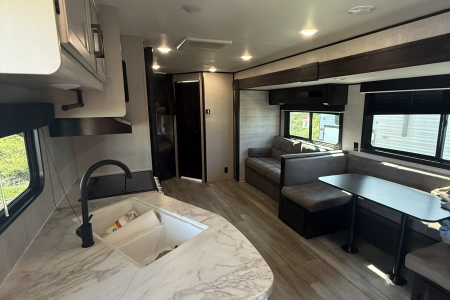 Spacious rv rental interior with modern kitchen, dining booth, and comfortable living area. Bright and clean.