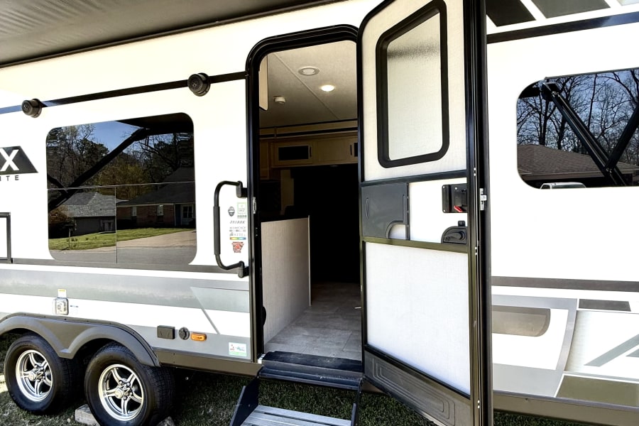 This RV rental showcases an open door with steps and an extended awning, inviting outdoor adventures.
