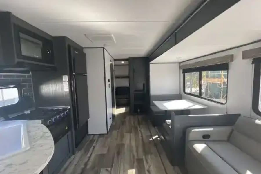 Modern RV rental interior featuring a full kitchen, comfy dinette, and sofa. Ideal for comfortable travels.