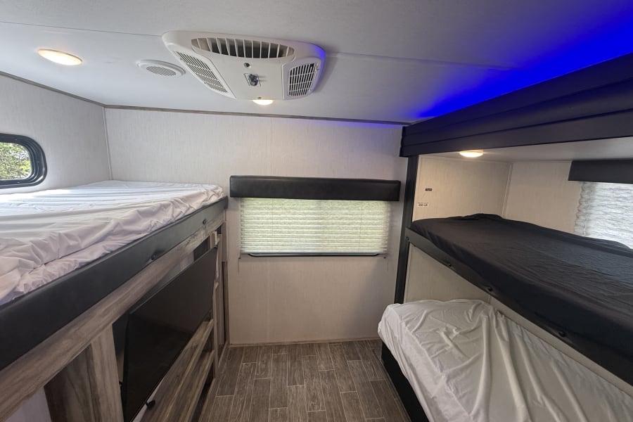 Cozy rv rental bunkhouse interior featuring multiple beds, AC, and ambient blue lighting for a comfortable stay.