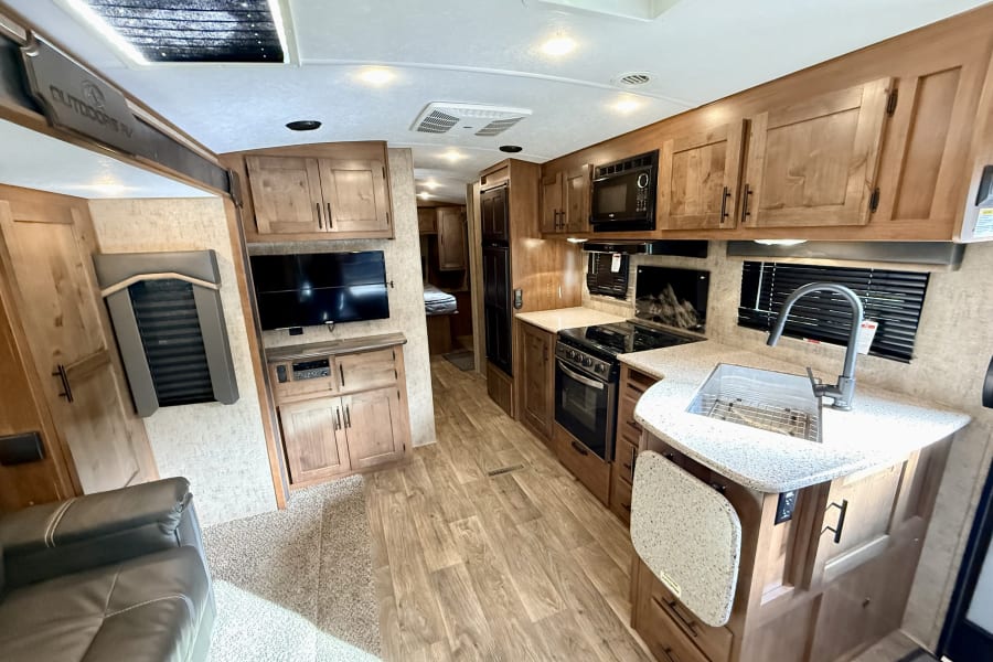 Explore this modern RV rental interior with a full kitchen, living space, and warm wood accents for a comfortable trip.