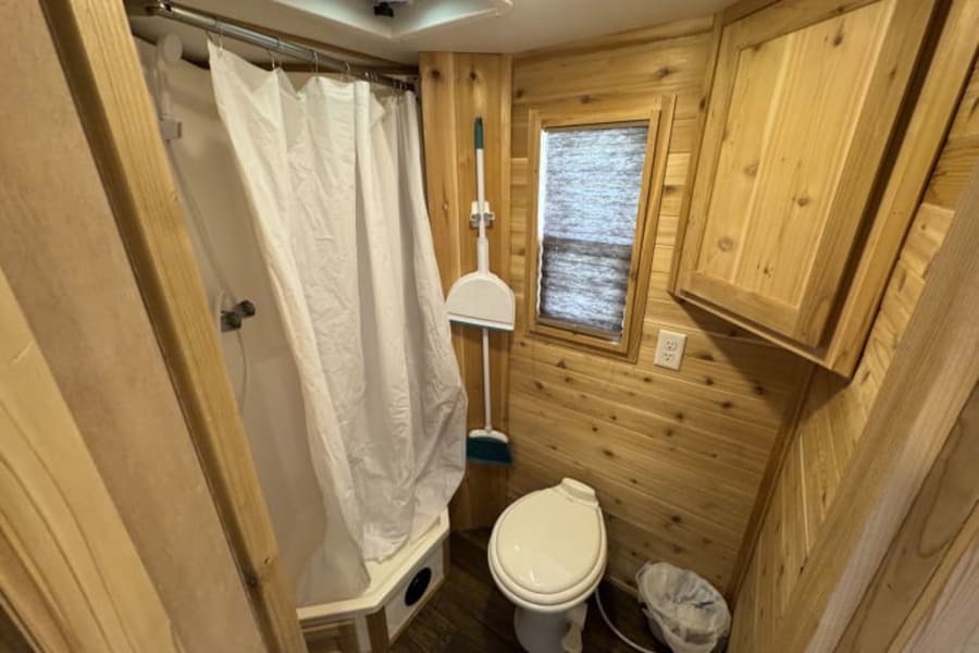 RV rental bathroom: compact wood-paneled shower & toilet. Essential amenities for your travel adventures.