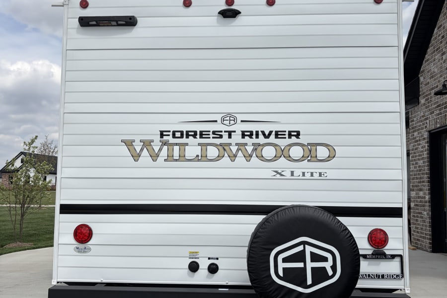 Forest River Wildwood X-Lite RV rental, showing the rear with camera, taillights, and spare tire. Ready for your next adventure!