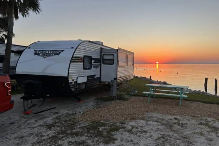 Enjoying a beautiful waterfront sunset at an RV campsite. This Wildwood RV rental offers stunning views and a relaxing outdoor experience.