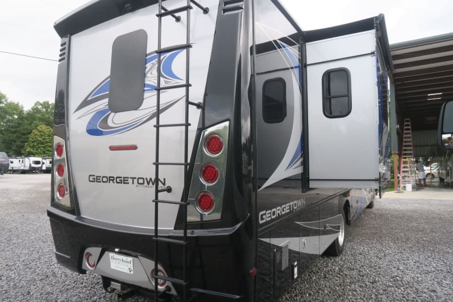 Georgetown RV rental. Rear view showing silver/black motorhome with ladder, red taillights, and extended side slide-out.