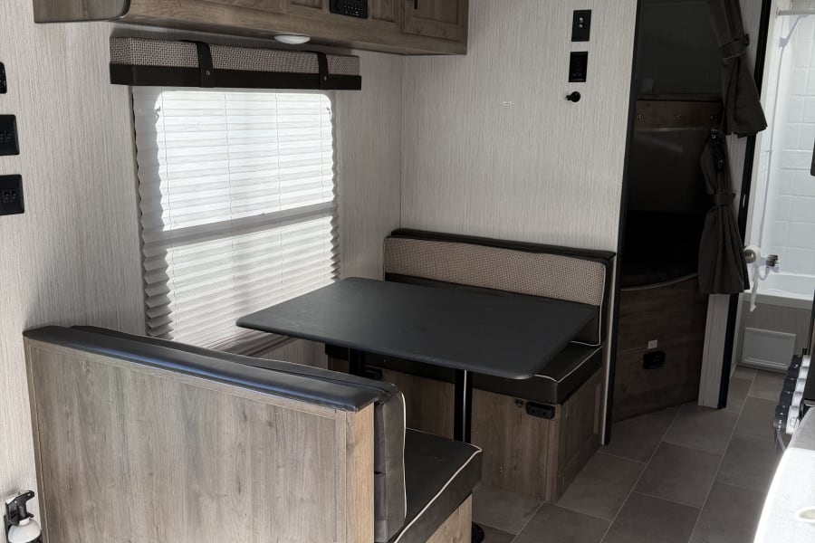 This modern RV rental features a dinette, kitchen, bunk beds, and bathroom access.