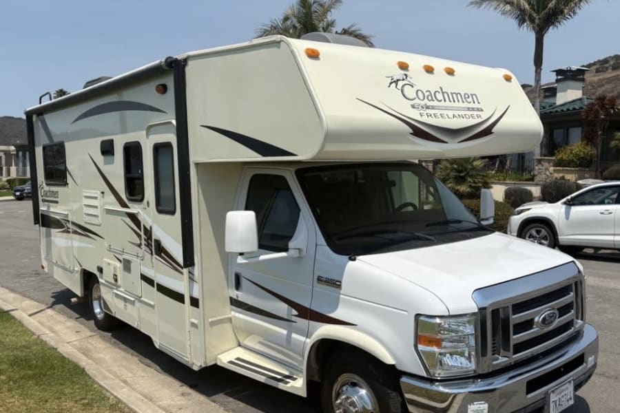 White Coachmen Freelander rv rental, a Class C Ford E-350 RV, parked on a sunny street with palm trees and houses.