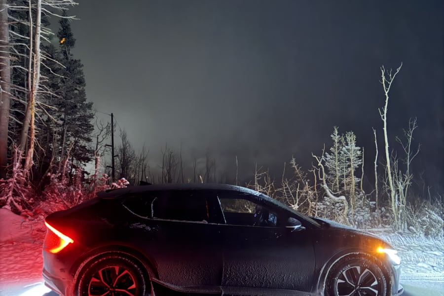 Modern car with glowing lights on snowy road at night among bare trees. Winter travel ready, explore **rv rental** options.