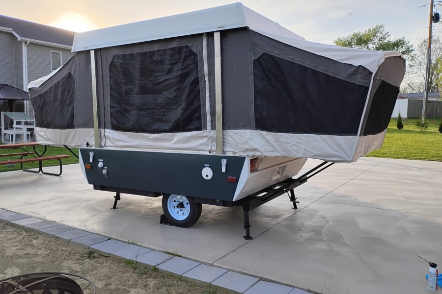 This fully extended pop-up camper, ready for a cozy getaway, makes for a great rv rental option for camping.
