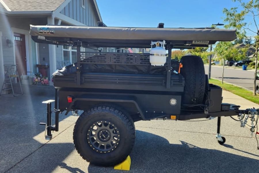 This rugged overland trailer, ideal for RV rental camping, has an awning, propane tank, and spare tire. Ready for adventure!
